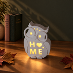 Kleine wachsame Keramik-Eulen – Motiv „HOME“ beleuchtet bei Nacht